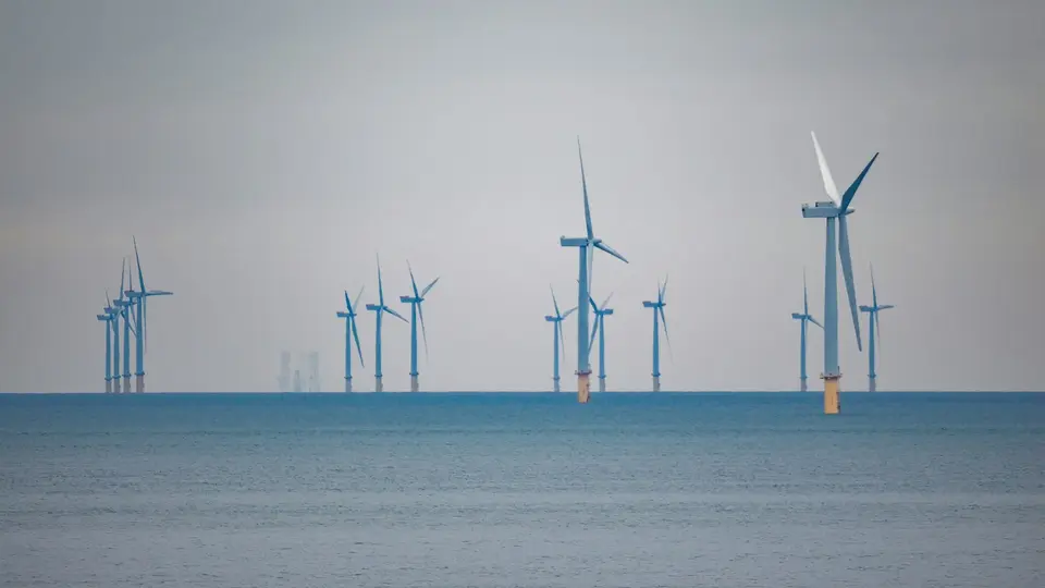 Windturbines in zee onder een grijze lucht